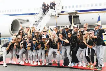  ?? Kathy Willens / Associated Press ?? Members of the United States women's soccer team, winners of a fourth Women's World Cup, pose with the trophy by their plane after arriving at the Newark, N.J., airport.