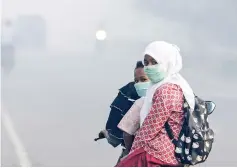  ?? — AFP photo ?? Motorists wear masks as they make their way along a road shrouded in thick smoke due to peat forest fires in Meulaboh, Aceh province.