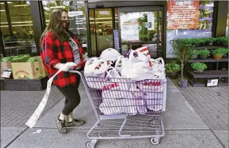  ?? KATHY WILLENS / AP ?? Alexandra Lopez-Djurovic heads to the parking lot with a receipt trailing behind her after shopping for a client at an Acme supermarke­t in Bronxville, N.Y. She was working full time as a nanny until her hours were cut amid the pandemic, so she started her own grocery delivery service to help fill gaps.