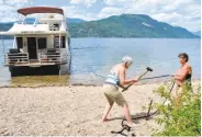  ?? Photos by Margo Pfeiff / Special to The Chronicle ?? Top: Heading toward the houseboat mother ship on Shuswap Lake. Above: The voyagers drive stakes into the beach to anchor the vessel for the night.