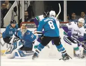  ??  ?? Vancouver’s Erik Gudbranson, with the Sharks’ Joe Pavelski (8) in pursuit, beats San Jose goalie Aaron Dell and Tim Heed for a goal on Thursday night.