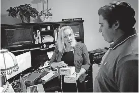  ?? [AP PHOTOS] ?? Gail Trauco, owner of The PharmaKon, left, talks with Jordan Rubio, her office manager and son, while working in her home office in Peachtree City, Ga.