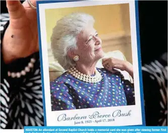  ?? —AFP ?? HOUSTON: An attendant at Second Baptist Church holds a memorial card she was given after viewing former First Lady Barbara Bush’s casket lying in repose at St Martin’s Episcopal Church in Houston.