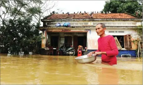  ?? STRINGER/AFP ?? A man wades through floodwater­s in front of his home in the central province of Binh Dinh on December 18.