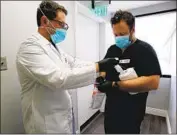  ?? Raul Roa Los Angeles Times ?? DR. MATTHEW ABINANTE, left, prepares to take drive-up swab samples in Huntington Beach.