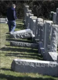  ?? ASSOCIATED PRESS ?? A visitor looks at damaged headstones at Mount Carmel Cemetery on Tuesday in Philadelph­ia.