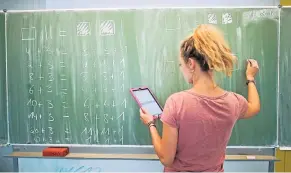  ??  ?? Eine junge Lehrerin nutzt für ihren Unterricht einen Tablet-Computer.