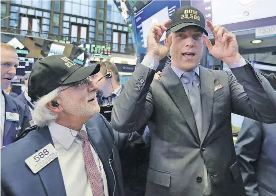  ?? [RICHARD DREW/THE ASSOCIATED PRESS] ?? Trader Peter Tuchman, left, and New York Stock Exchange President Tom Farley don caps marking “Dow 23,500,” on the trading floor as the index crosses the milestone. The stock market may have appeared to Donald Trump as “a big bubble” before he was...
