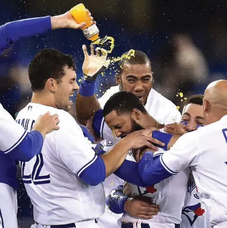  ?? FRANK GUNN/THE CANADIAN PRESS ?? The Jays’ Richard Urena, centre, is mobbed by teammates after hitting a game-winning RBI single in the ninth inning Tuesday night against the Orioles.