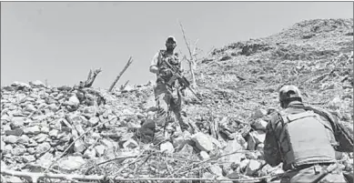  ??  ?? Afghan soldiers stand on the place where the largest convention­al bomb was dropped by the US killing 94 Isis militants. (Photo: Xinhua)