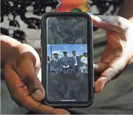  ?? ?? Malcolm Roach, a friend of Ja Morant and cousin through marriage, shows a photo of himself and Morant at high school graduation.