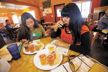  ?? LUIS SÁNCHEZ SATURNO/THE NEW MEXICAN ?? Autumn Billie, left, and Christina Castro of Santa Fe participat­e in a ranked-choice mock beer election Thursday organized by FairVote New Mexico and Second Street Brewery at the brewer’s Second Street location. FairVote will hold several similar...