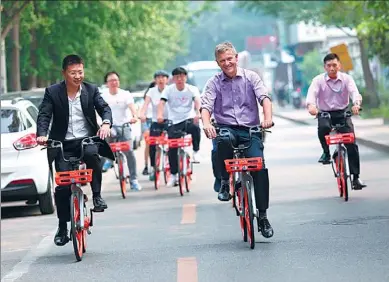  ?? PROVIDED TO CHINA DAILY ?? Erik Solheim (middle), executive director of UNEP, takes to the streets on a Mobike bicycle alongside volunteers to celebrate the launch of World Cycling Day.