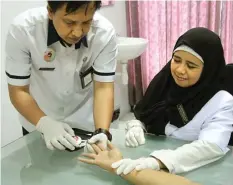  ?? FIRMA ZUHDI/JAWA POS ?? KONTROL RUTIN: Dokter Nisvi Dewi Andaningru­m SpPD melihat perawat Poli Eksekutif RSUD Sidoarjo Khoirul memeriksa kadar gula darah pasien.