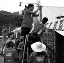  ??  ?? Volunteers from Pepsi Philippine­s install a solar street light in Barangay New Kawayan, under the watchful eye of Liter of Light project head Illac Diaz III.