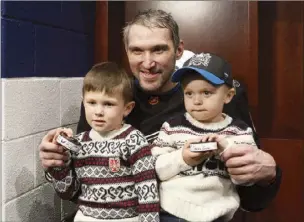  ?? AP photo ?? Alex Ovechkin poses with his children Sergei (left) and Ilya and the pucks he scored goals 801 and 802 with during Friday’s game.