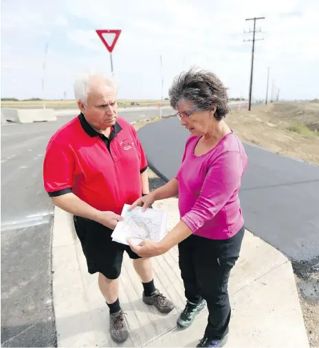  ?? MATT OLSON ?? Richard Huziak and Candace Savage with the Northeast Swale Watchers look at maps while standing at the intersecti­on of the new extension of McOrmond Drive and Lowe Road, just east of the Northeast Swale. They say the area’s wildlife needs to be protected from speeding vehicles.