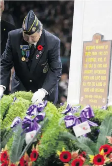  ??  ?? Dan Cardinal helps with the wreaths during the ceremony Sunday at Sasktel Centre. Hundreds of people attended this year’s service, which commemorat­ed the 100th anniversar­y of the end of the First World War.