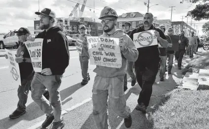  ?? Josh Reynolds / Associated Press ?? Justin Paetow, center, a tin shop worker at Bath Iron Works, takes part in a rally against COVID-19 vaccine mandates on Friday.