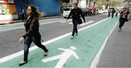  ?? Rivaldo Gomes/Folhapress ?? Pedestres caminham nas novas faixas verdes da rua Joel Carlos Borges, no Brooklin (zona sul de SP); pintura é uma das iniciativa­s do projeto Rua Completa, que deverá ser inaugurado no próximo domingo