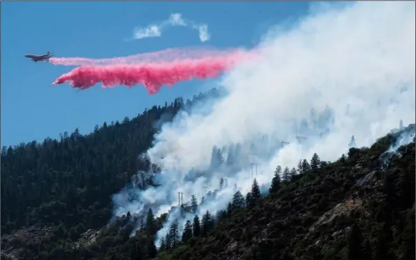  ??  ?? An air tanker drops fire retardant Wednesday to battle the Dixie Fire in the Feather River Canyon in Plumas County, Calif. (AP/The Sacramento Bee/Paul Kitagaki Jr.)