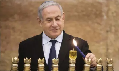  ??  ?? Benjamin Netanyahu lighting a Hanukkah candle earlier on Wednesday. Photograph: Sebastian Scheiner/AFP/Getty