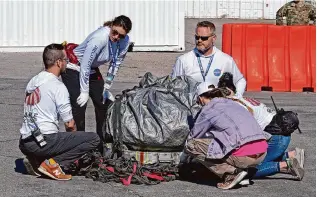  ?? Photos by Rick Bowmer/Associated Press ?? Recovery team members examine a capsule containing NASA’s first asteroid samples Sunday before it is taken to a temporary clean room at Dugway Proving Ground in Utah.
