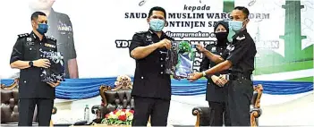  ??  ?? Mazli presenting the contributi­on to one of the recipients, witnessed by Lahad Datu Police Chief, ACP Rohan Shah Ahmad (left).