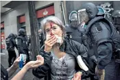  ??  ?? Violence: an injured woman in front of riot police near a polling station for the referendum; main, Catalans wear the
Estelada, the pro-independen­ce flag