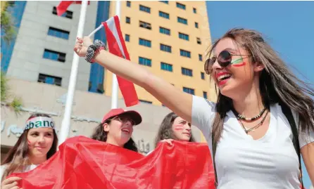  ?? — AFP ?? Lebanese students wave the national flag and chant slogans as they gather outside the Ministry of Education and Higher Education during ongoing antigovern­ment protests, in the capital Beirut on Friday.