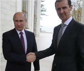  ?? Ap fiLE pHOTOS ?? PAYING A DEBT: Russian President Vladimir Putin, left, shakes hand with Syrian President Bashar Assad in the Bocharov Ruchei residence in the Black Sea resort of Sochi, Russia, on Nov. 20, 2017. The Syrian dictator is sending reinforcem­ents to Putin, who is currently caught in a quagmire in Ukraine. Below, local residents walk past destroyed Russian tanks in Chernihiv region, Ukraine, on Friday.