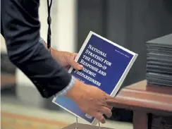  ?? Mandel Ngan, AFP ?? An aide collects copies of the National Strategy for COVID-19 before President Joe Biden addressed the response and signed executive orders in the State Dining Room of the White House in Washington, DC, on Thursday.