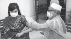  ??  ?? PESHAWAR
A health worker injecting COVID-19 vaccine to a teacher at Shaheed Benazir Bhutto Women University. -APP