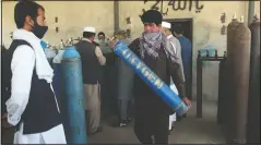  ??  ?? A man carries an oxygen tank from a privately owned oxygen factory in Kabul.