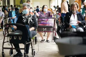  ?? The Associated Press ?? Q Resident Sabeth Ramirez, 80, center, waits in line with others for the Pfizer-BioNTech COVID-19 vaccine Wednesday at the The Palace assisted living facility in Coral Gables, Fla.