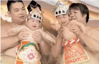  ?? — AFP ?? Sumo wresters hold up crying babies at the “Baby-cry Sumo” event at the Kamegaike-Hachiman Shrine in Sagamihara, Kanagawa prefecture, on Sunday.