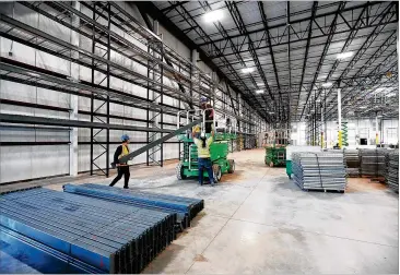  ?? CURTIS COMPTON / CCOMPTON@AJC.COM ?? Constructi­on workers assemble industrial storage shelving inside the LTI Inc. food service equipment manufactur­er building. The expansion of the longtime Clayton company is a win for the county.