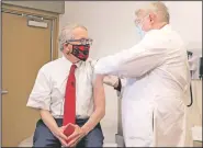  ?? (Courtesy Photo/Ohio Governor’s Office) ?? Gov. Mike DeWine (left) gets his first dose of the covid-19 vaccine on Feb. 2 from Dr. Kevin Sharrett, in Jamestown, Ohio. On Friday, The Associated Press reported on stories circulatin­g online incorrectl­y asserting masks are no longer mandatory in Ohio, and DeWine isn’t saying a word about it. But masks remain mandatory in Ohio in indoor spaces as well as outdoors when social distancing is not possible.