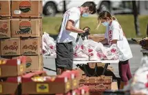  ?? Brett Coomer / Staff photograph­er ?? YMCA employees fill and distribute bags of fresh produce at the North Houston Skate Park in April.