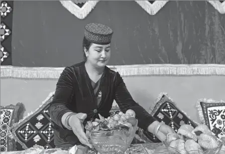  ?? XING WEN / CHINA DAILY ?? A resident in Tashikurga­n county, Xinjiang Uygur autonomous region, who runs a homestay, serves her customers with fresh fruits in August.