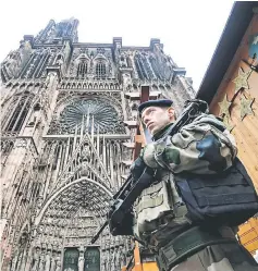  ??  ?? French soldiers stand guard at the Christmas market in front of the Cathedral as policemen conduct a search for the gunman. — AFP photo