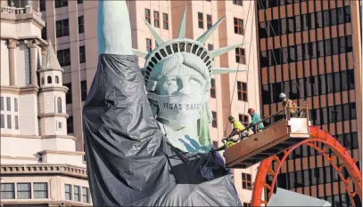  ?? K.M. Cannon Las Vegas Review-journal @Kmcannonph­oto ?? At least somebody’s in the spirit: Workers install a a Raiders jersey on the Statue of Liberty replica at New York-new York.