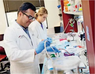  ?? [PHOTO BY NATE BILLINGS, THE OKLAHOMAN ARCHIVES] ?? Vishal Chandra, postdoctor­al fellow, left, and Cassadie Holybee, an undergradu­ate from Cameron University, are shown in this June 22 photo working on a cervical cancer drug at the Stanton L. Young Biomedical Research Center. A new report suggests the...