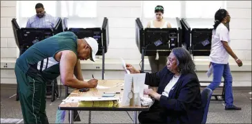  ?? TRAVIS DOVE / THE NEW YORK TIMES ?? A North Carolina election worker checks a voter’s identifica­tion at an elementary school in Charlotte. North Carolina’s voter ID law, which also abolished same-day voter registrati­on and ended preregistr­ation, was held as discrimina­tory and struck down...