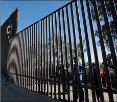  ?? AP PHOTO/GREGORY BULL ?? In this 2018 file photo, boys look through an older section of the border structure from Mexicali, Mexico, alongside a newly-constructe­d, taller section, left, in Calexico, Calif.