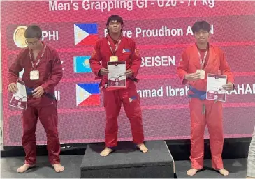  ?? PHOTOGRAPH COURTESY OF UWW ?? FIERRE Afan (center) steps on the medal podium after clinching two gold medals in the 2024 United World Wrestling Asian Grappling Championsh­ip.