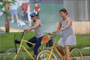  ?? MICHILEA PATTERSON — FOR MEDIANEWS GROUP ?? Two women ride bicycles during a Sustainabi­lity Fair in Royersford. The bikes were able to be used for free as part of the bike share program available in Pottstown through the Schuylkill River Greenways National Heritage Area.