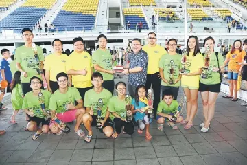  ??  ?? PASC president Tan Kun Gee receives the challenge trophy from Wee (fifth right) as Lau (third left), organising committee members and the best swimmers look on. — Photo by Mohd Rais Sanusi