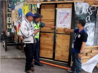  ?? Photo by Bong Cayabyab ?? CLOSED!!! City Licensing Officer Allan Abayao, police station area commander inspector Julius Basinga and Punong barangay Jose Acosta implement the Administra­tive order of Mayor Mauricio Domogan for operating without a business permit and for various...