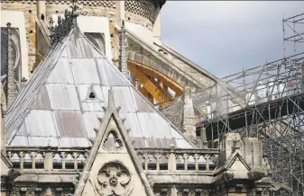  ?? Francois Mori / Associated Press ?? Workers in protective clothing cross a walkway at Notre Dame Cathedral in Paris. Authoritie­s had halted reconstruc­tion work in July over fears of lead contaminat­ion at the site.